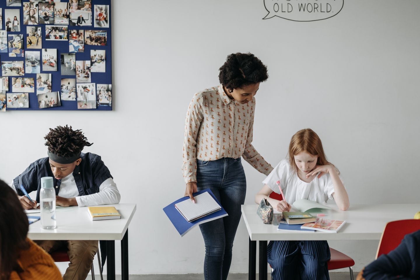 A teacher bending to check a pupil's work in a classroom