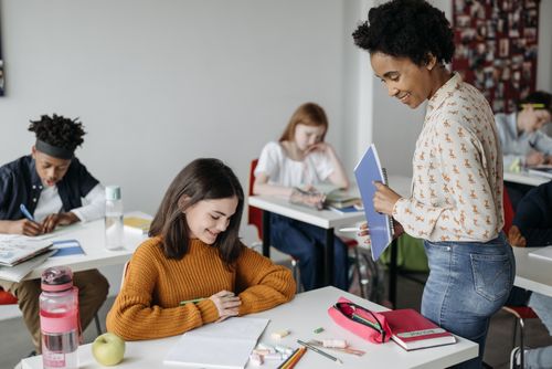 Free Teacher assisting students in a classroom setting, fostering a learning environment. Stock Photo