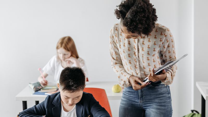 A teacher guides a group of students working together in a modern classroom