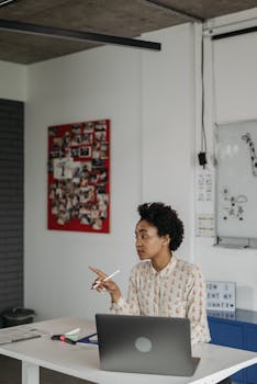 African American woman engaging with students in a well-lit modern classroom setting.