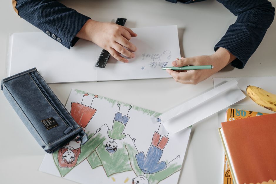 A child drawing with a pencil on a notebook, showing creativity and fine motor skills.