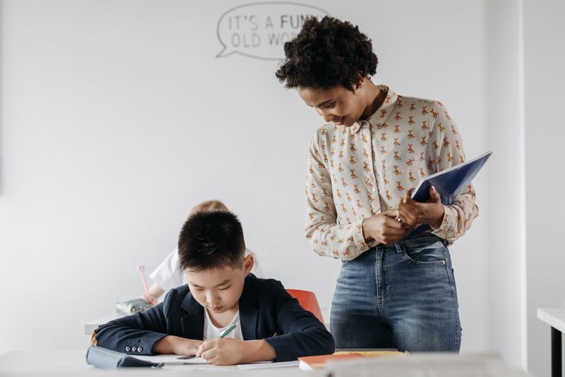 An adult supporting a pupil one to one, looking over their work together