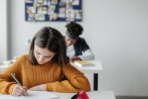 Free Girl in Knitted Sweater Writing on her Notebook Stock Photo