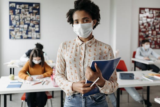 African American teacher in a classroom wearing a face mask with students working.