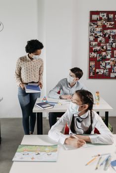 Students and teacher wearing masks in a classroom, practicing safe learning during COVID-19.