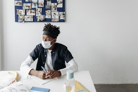 Young student with mask at desk in modern classroom, learning during pandemic.