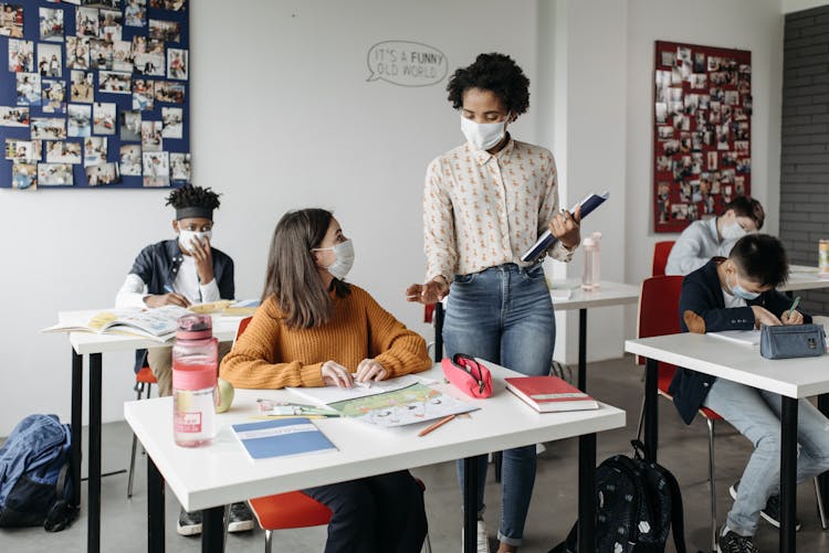 Teacher And Students Wearing Facemasks In Attending School