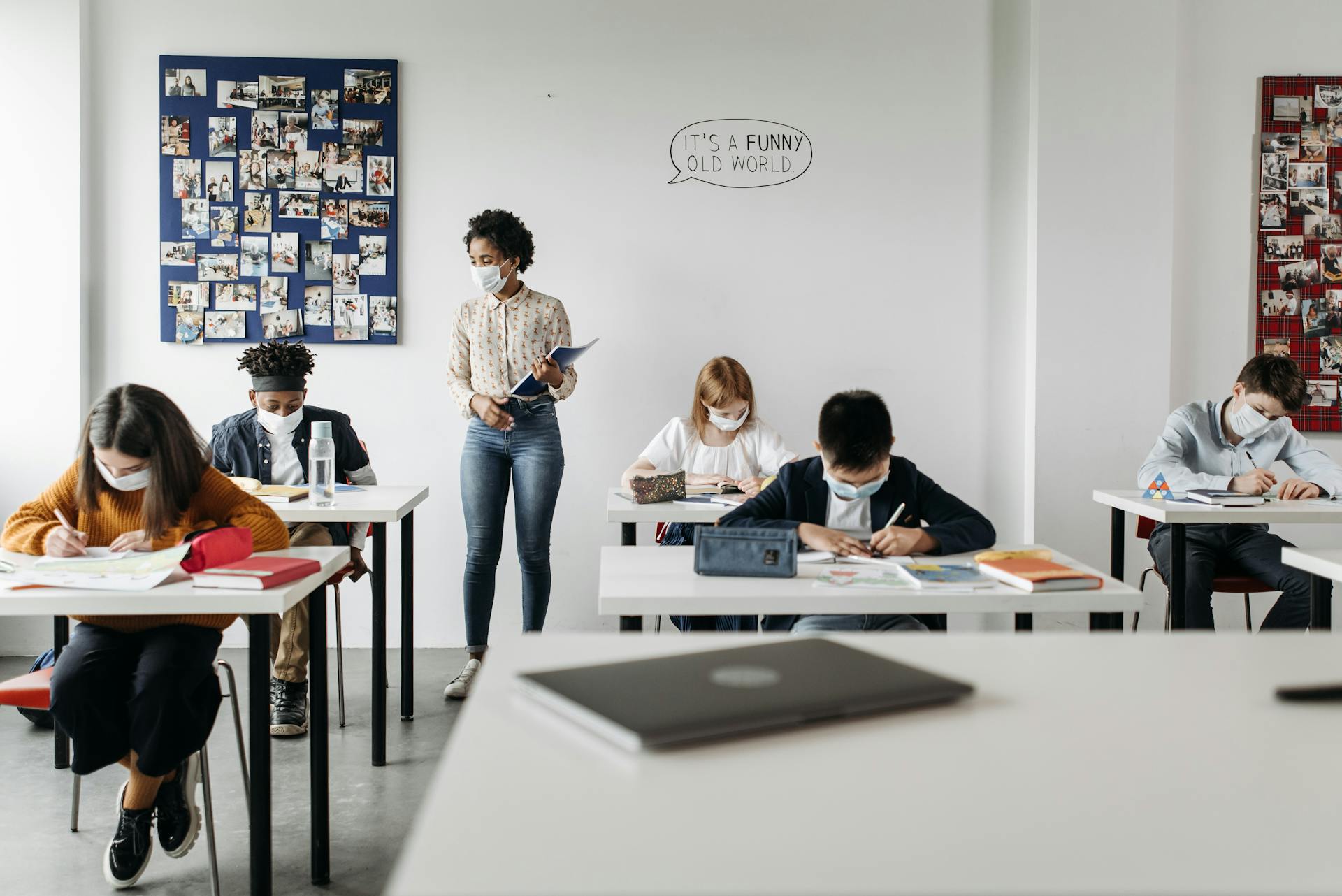 Students and teacher in a classroom wearing masks, embracing new normal education setting.