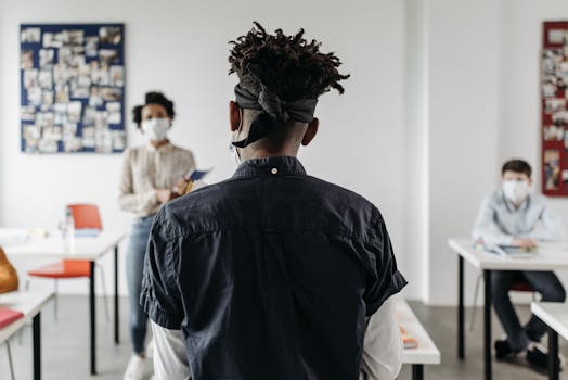 Back view of a student presenting in a classroom with peers wearing masks, focusing on education during pandemic.