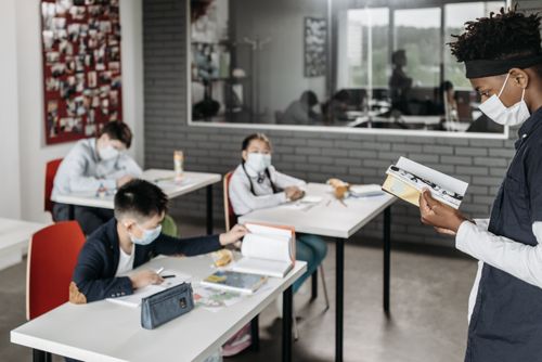 Free Students wearing masks in a classroom setting during a lesson, maintaining focus on education. Stock Photo