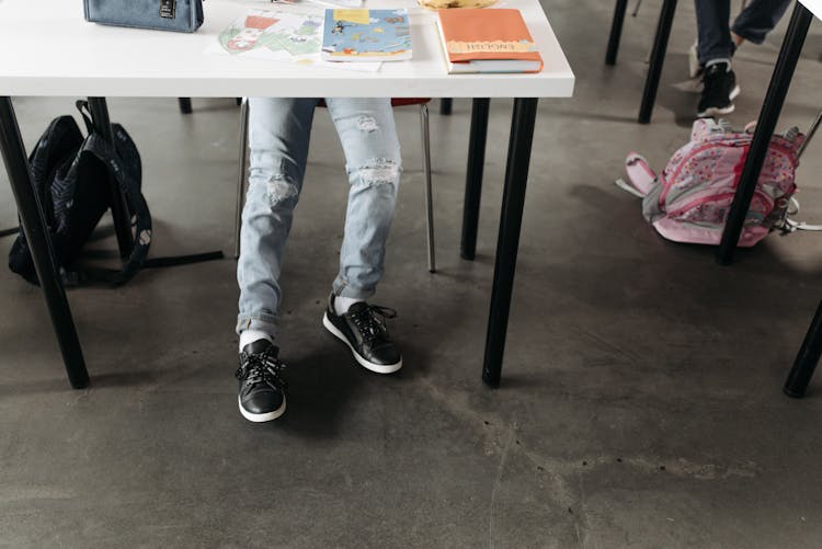 A Student Wearing Ripped Jeans And Black Sneakers In School