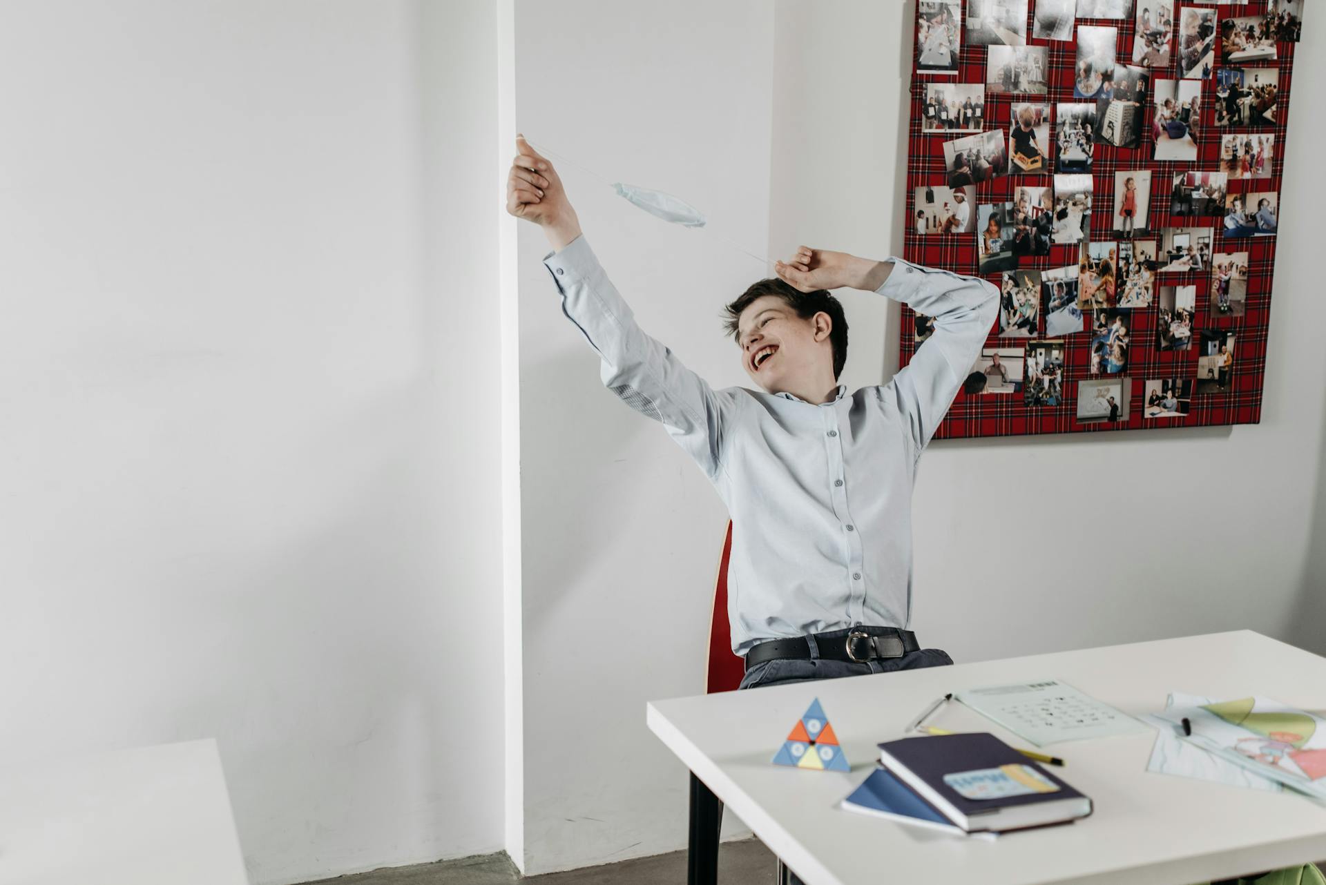 Teen celebrating in a classroom by tossing a face mask, symbolizing relief and happiness.