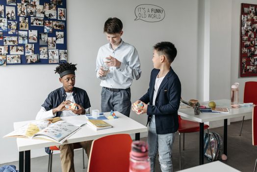 Three diverse students engaging in a lively classroom setting, discussing and sharing ideas.