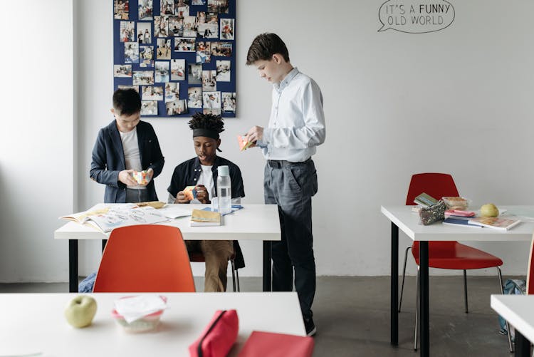 Three Boys In The Classroom Playing With Rubik's Cube