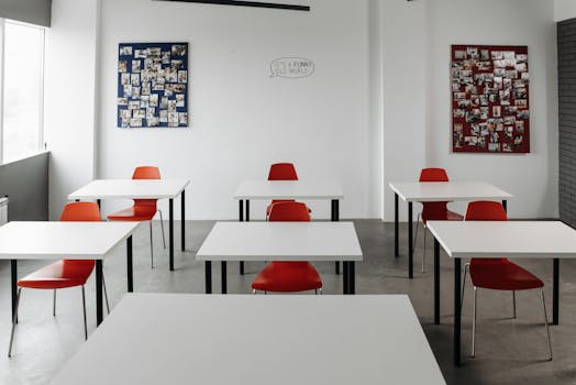 Spacious modern classroom featuring red chairs and white desks, ideal for education themes.
