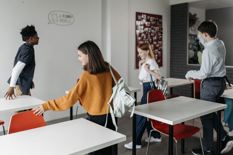 A group of cheerful students leaving a classroom, indicating a positive school environment.