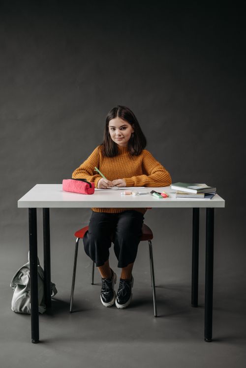 Free A young girl concentrates on her studies at a minimalist desk, creating an educational setting. Stock Photo