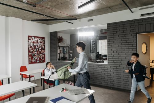Free Children organizing backpacks and tasks in a modern classroom setting. Stock Photo
