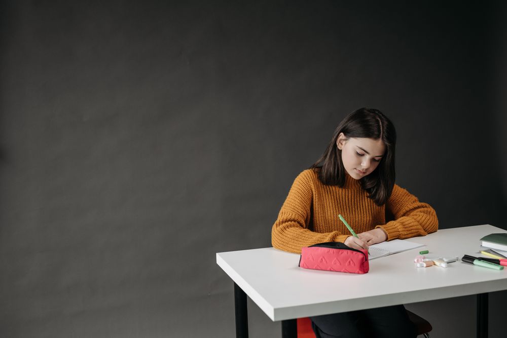 A schoolgirl writing in her notebook at a classroom desk