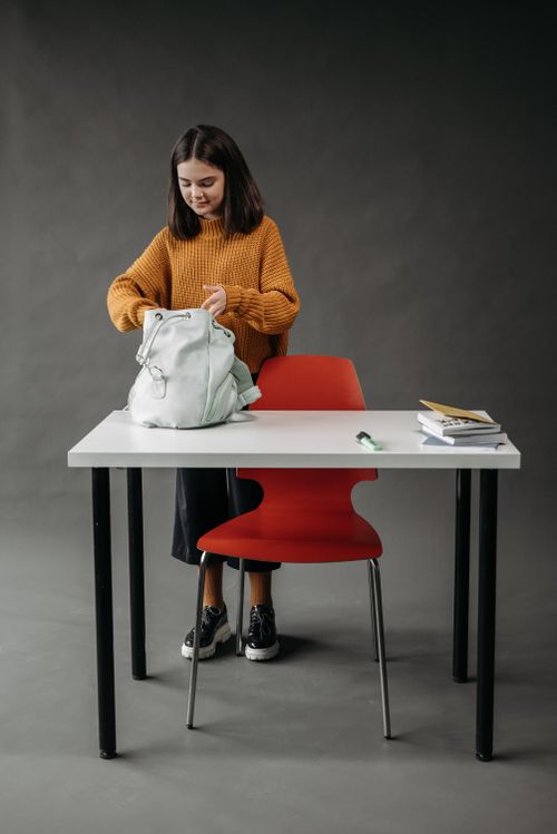 Free Teenage student with backpack and books in studio setting, organizing belongings. Stock Photo
