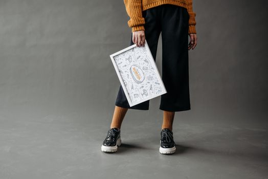 A young adult holds an educational poster in a stylish studio setting. Conceptual image for education.
