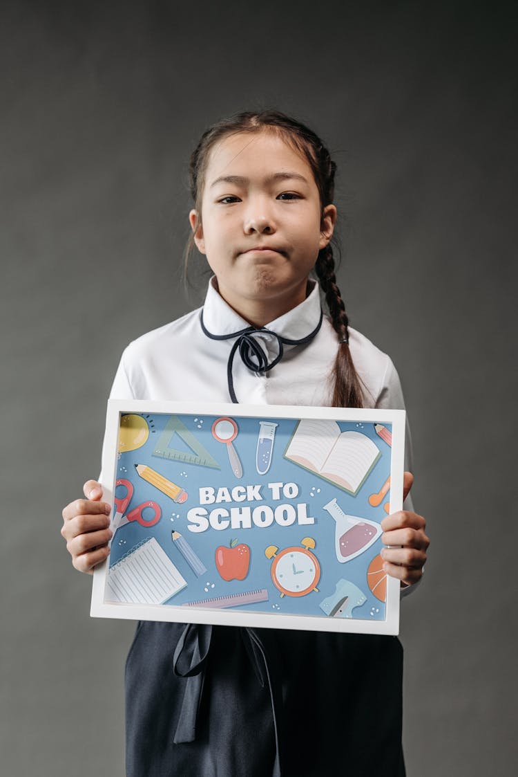 A Girl Holding A Back To School Poster