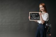 Young girl holding a 'Back to School' chalkboard, ready for the school year.