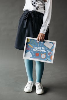 A student holding a back to school poster with educational symbols in a studio setting.