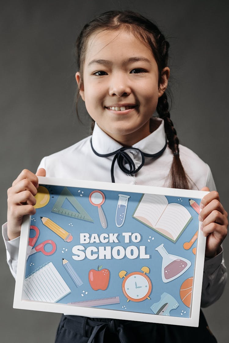 A Girl Holding A Back To School Poster