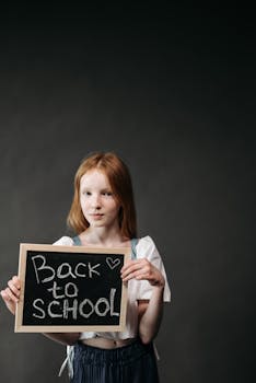 A young girl holds a chalkboard with 'Back to School' text, ready for new school year.