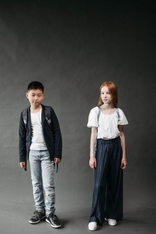 Free Stylish teenagers posing in studio with backpacks against a gray background. Stock Photo