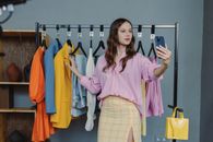 Woman in Pink Dress Shirt Standing Near Clothes Rack