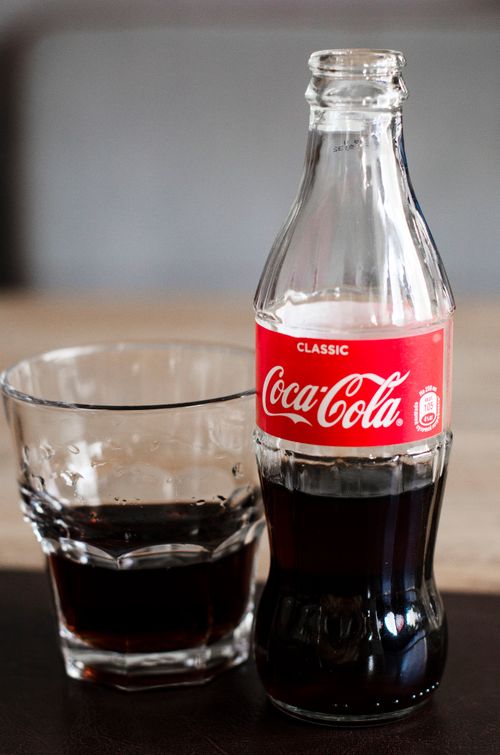 Free A classic Coca-Cola bottle next to a glass on a wooden table, exuding refreshment. Stock Photo
