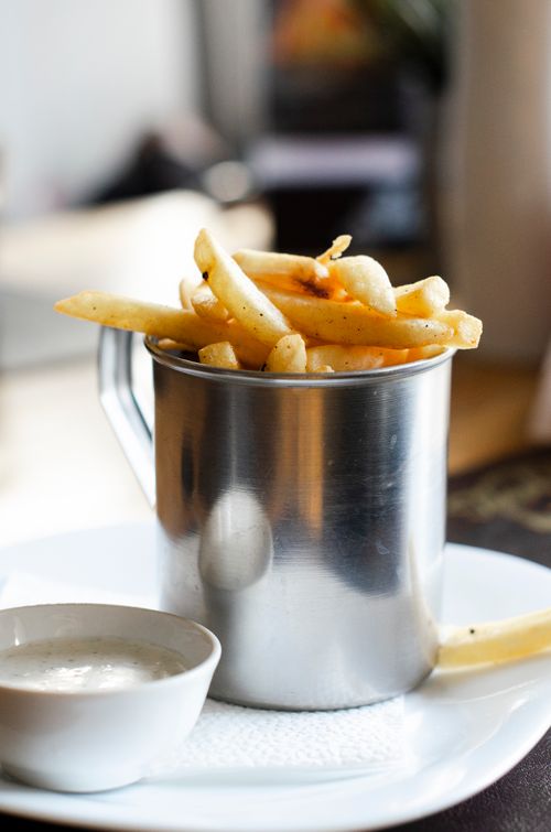 Free Tasty french fries served in a sleek steel cup with a side dipping sauce, perfect for a quick snack. Stock Photo