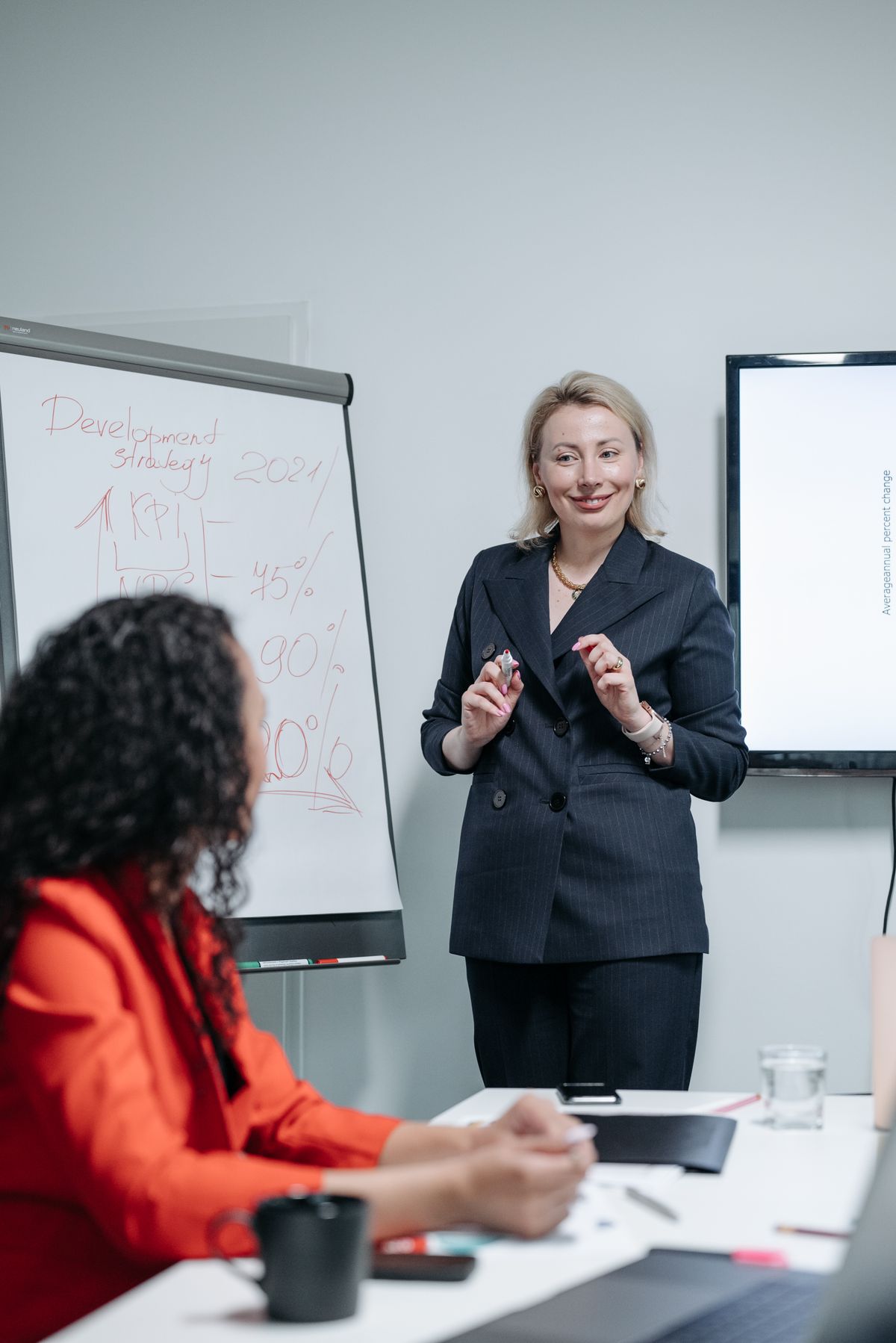 A businesswoman presenting a strategy on a whiteboard during a team meeting