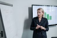 Woman in Black Coat Standing Near White Wall