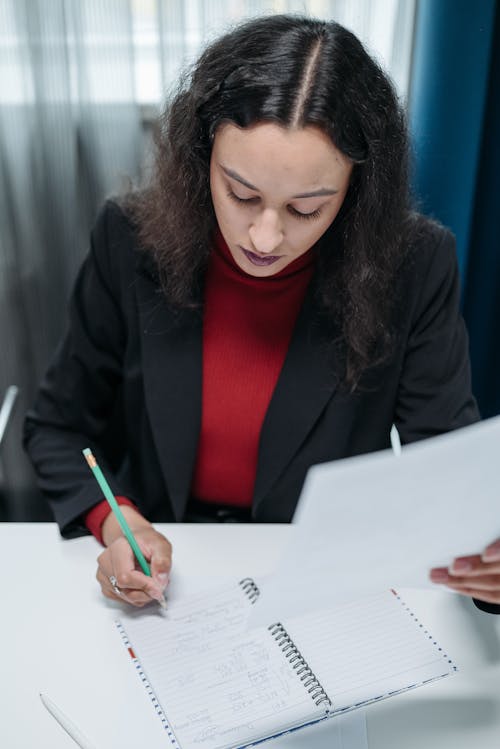 Woman in Black Blazer Writing on Notebook