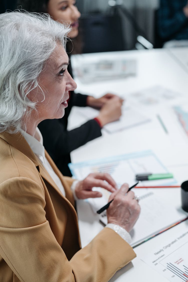 Woman In Brown Blazer Holding A Pen