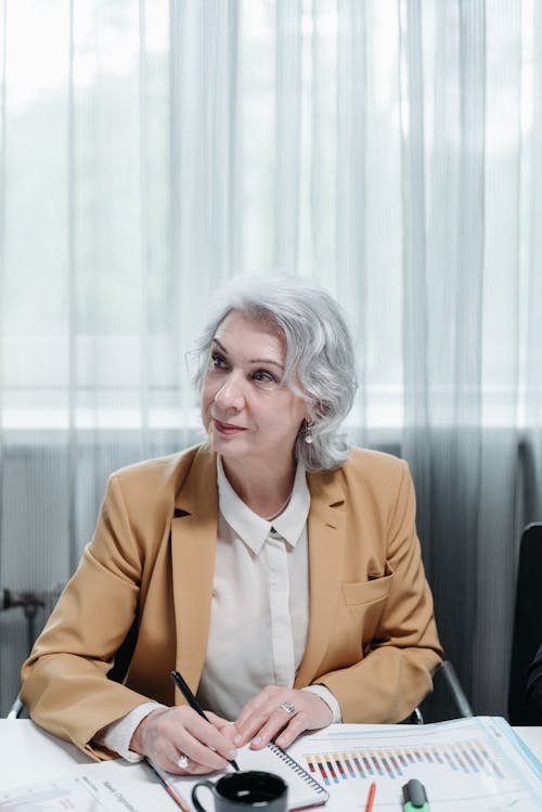 Free Woman in Brown Blazer Sitting by the Table Stock Photo