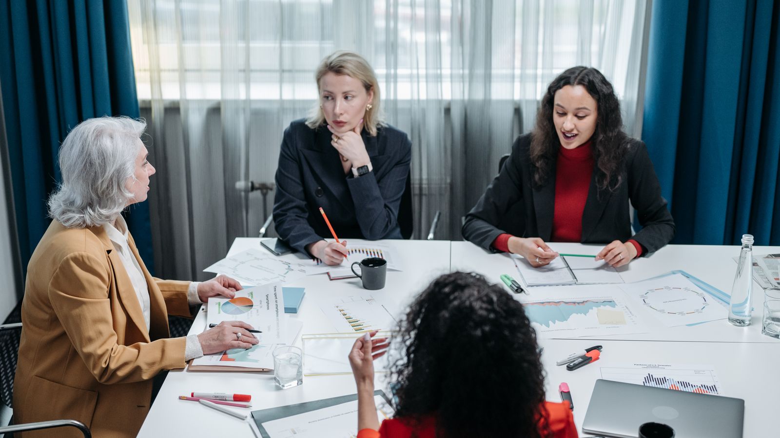 Four professional women engaged in a productive office meeting, discussing business plans.