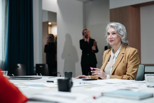 Confident senior businesswoman with gray hair in a meeting room, leading a discussion.