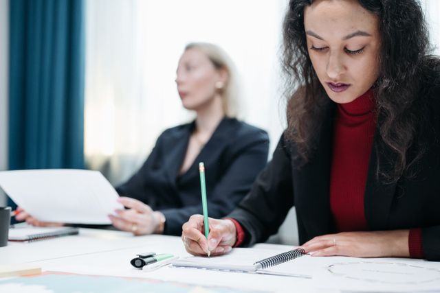 Deux professionnelles prenant des notes pendant un entretien de préparation d'un bilan de compétences