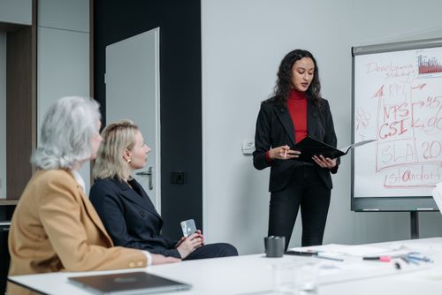 Free Three business women in a modern office holding a team meeting with presentations and discussions. Stock Photo