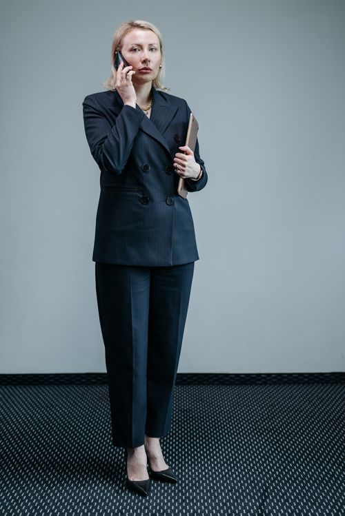 Free Caucasian businesswoman in black suit speaking on smartphone indoors. Stock Photo