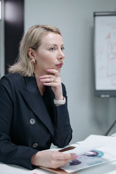 Focused businesswoman in corporate attire during a meeting, deep in thought.