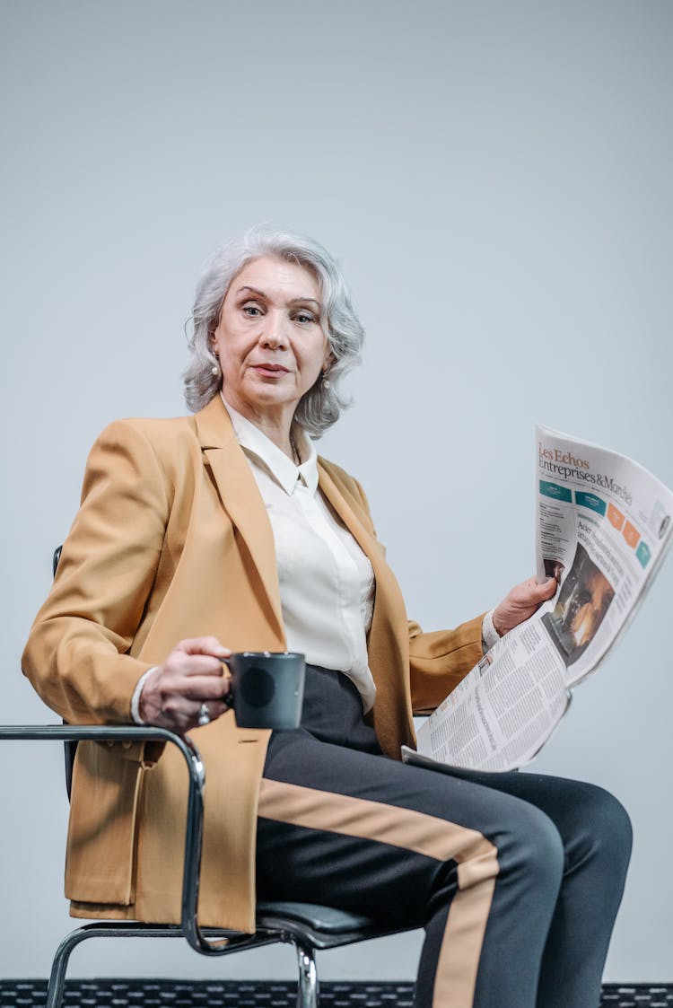 A Woman Holding A Newspaper And Cup Of Coffee 