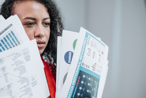 Free A businesswoman analyzing complex documents in a modern office setting. Stock Photo