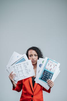 Confident woman in red suit examining various charts and graphs in an office setting.