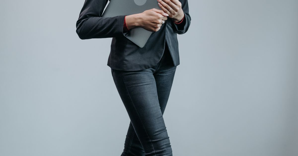 Woman in dark jeans with tailored blazer at work