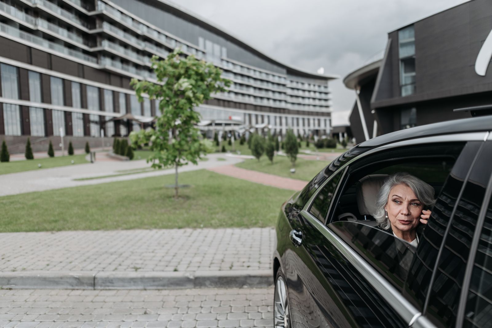 Senior passenger seated in a car outside a large building